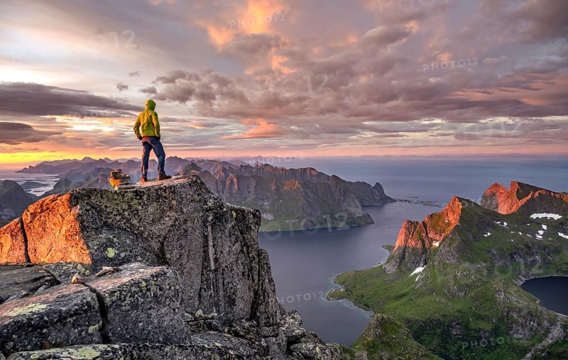 View over mountain top and sea, dramatic sunset, climbers at the top of Hermannsdalstinden, with Fjord Forsfjorden, Moskenesöy, Lofoten, Nordland, Norway, Europe
