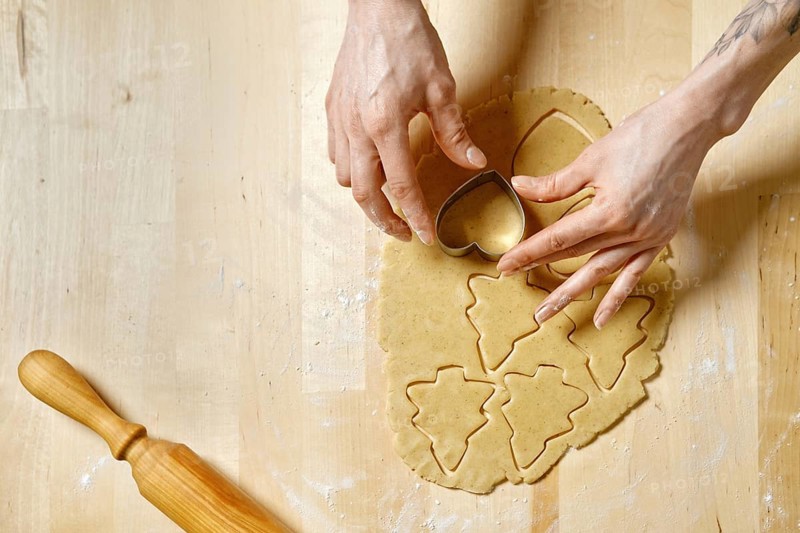 Top view at hands of unrecognizable woman cutting out biscuits from dough with cookie cutter