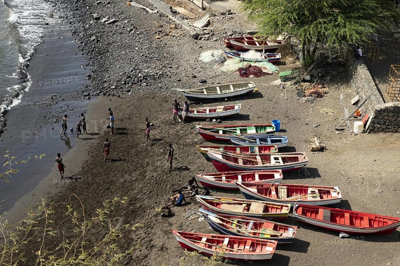 Youth playing soccer on the beach in front of traditional wooden fishing boats, Cidade Velha on the island of Santiago, Cape Verde, Cabo Verde, Africa