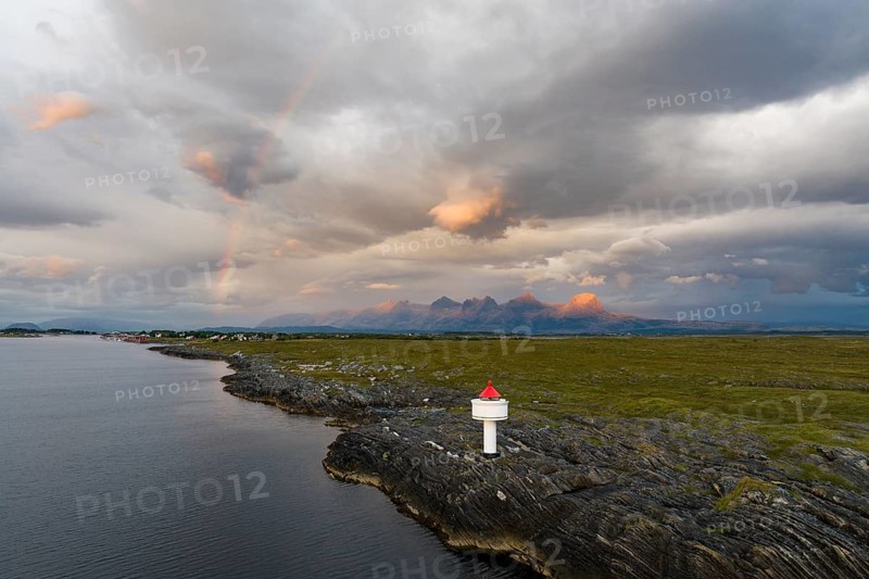 Small lighthouse at the coast, behind the mountain range Seven Sisters, light mood with rainbow, Heroy island, Helgeland coast, Nordland, Norway, Europe