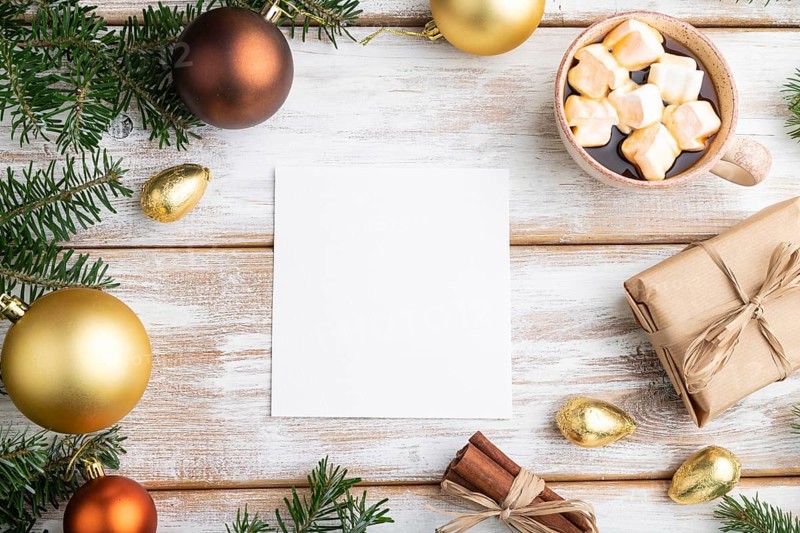 Christmas or New Year frame composition, template. Decorations, box, golden balls, cinnamon, fir and spruce branches, cup of coffee, on a white wooden background. Top view, copy space, flat lay