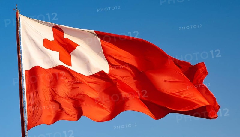 The flag of Tonga, Pacific island state, flutters in the wind, isolated against a blue sky