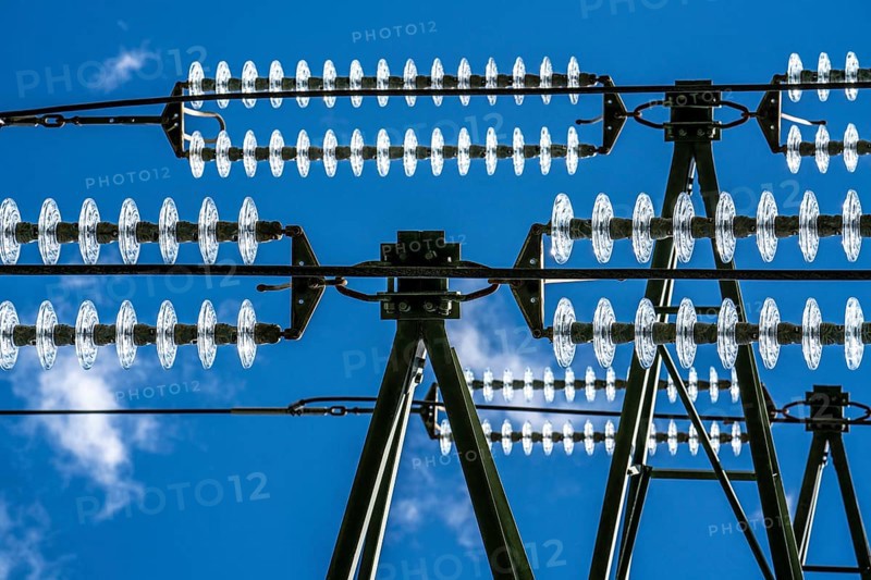 Insulators made of glass on a high-voltage line, they hang on the pylons as a suspension device between the pylon and the live, non-insulated cable, extra-high voltage line, symbolic image energy