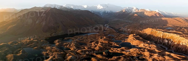 PanoramaWhite glaciated and snow-covered mountain peak Pik Lenin at sunrise, hilly landscape with golden yellow meadows and lakes, aerial view, Trans Alay Mountains, Pamir Mountains, Osher Province, Kyrgyzstan, Asia