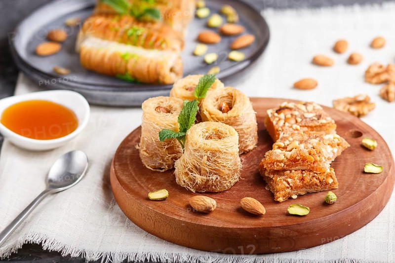 Set of various traditional arabic sweets: baklava, kunafa, basbus in ceramic plates on a gray concrete background. side view, selective focus