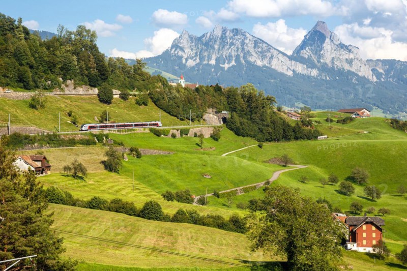 Railway passenger train of the type Stadler Flirt of the Südostbahn on the mountain GroÃŸer Mythen in the Alps in Arth, Switzerland, Europe