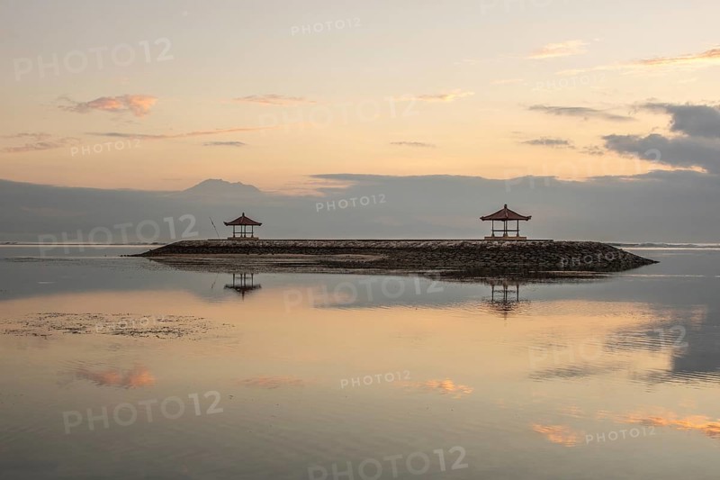 Beautiful seascape in the morning. Tropical sandy beach with breakwater and reflection of the sky in the calm water. Morning landscape, taken in Sanur, Bali, Indonesia, Asia
