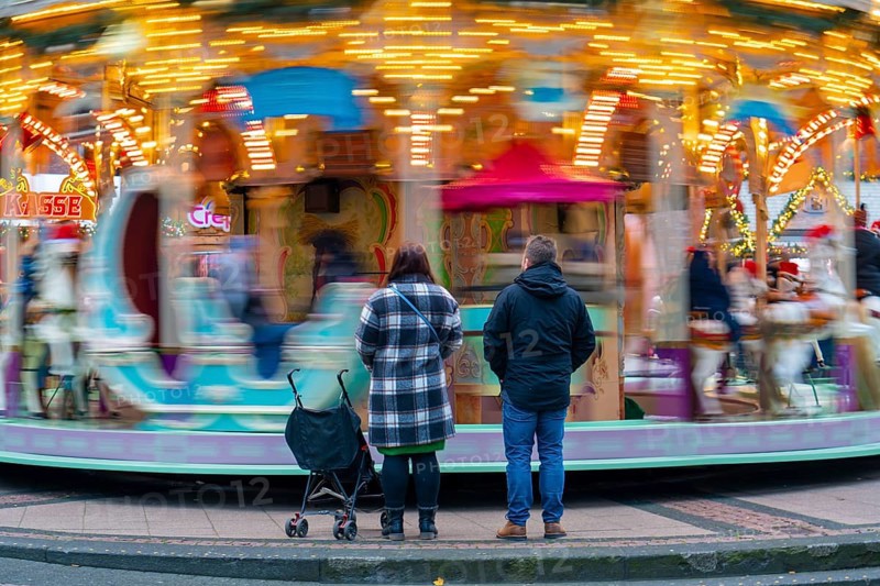 Pre-Christmas season, Christmas market at Kennedyplatz in the city centre of Essen, carousel, parents watching their child riding the carousel, North Rhine-Westphalia, Germany, Europe