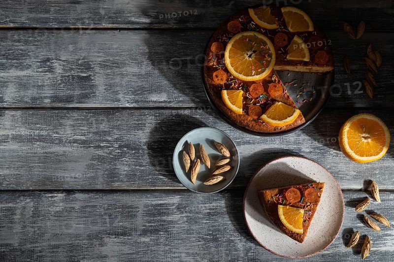 Orange cake on a gray wooden background. Hard light. contrast, low key. Top view, flat lay, copy space