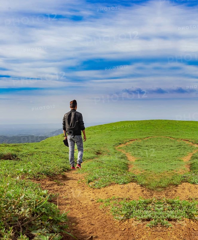 View of backpacker man walking on the beautiful hill. Backpacker walking on a beautiful hill