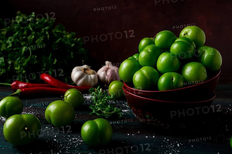Tkemali, green cherry plum, with ingredients for sauce, cilantro, mint, hot pepper, garlic, on a wooden table, close-up, rustic, food background, no people, selective focus