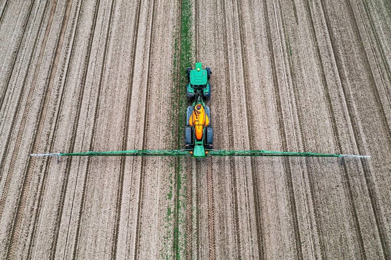 Farmer working a field, crop protection agent being sprayed, field with young sugar beet plants, North Rhine-Westphalia, Germany, Europe