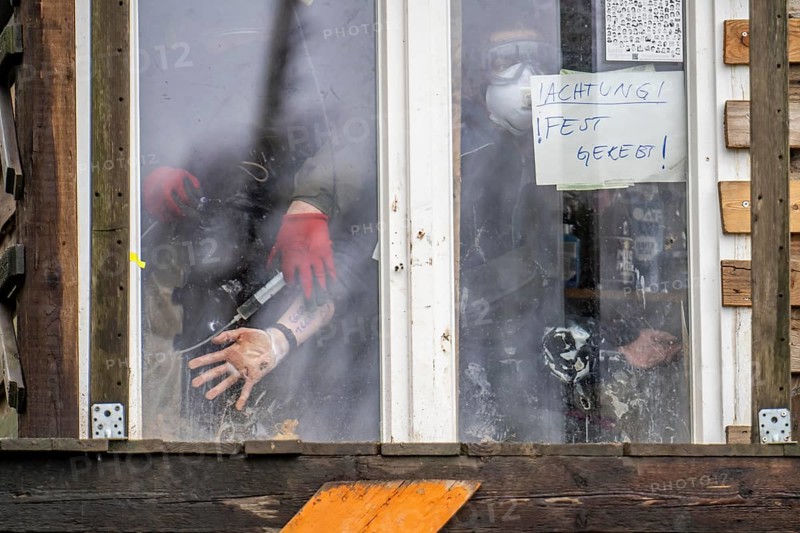 2nd day of the eviction of the hamlet Lützerath, by the police, of tree houses and huts, activist has glued herself to the glass pane of a window, from the inside, police removes the glue, at the opencast lignite mine Garzweiler 2, Erkelenz, North Rhine-Westphalia, Germany, Europe