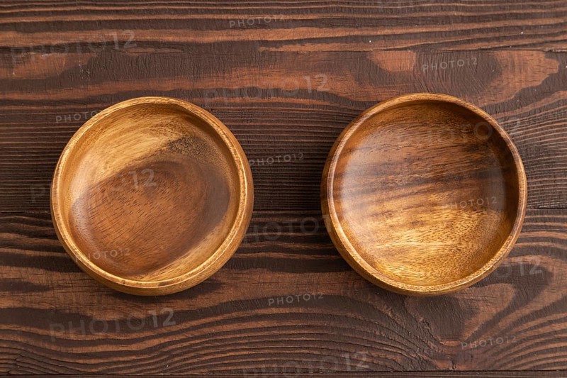 Two empty brown wooden bowl on brown wooden background. Top view, copy space, flat lay