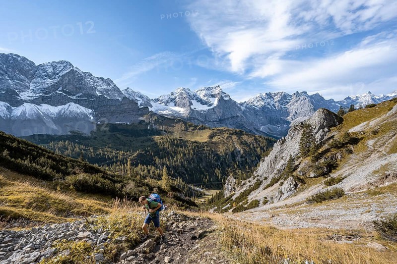 Mountaineers climbing up a hiking trail, mountain panorama with steep rocky peaks, yellow-coloured larches in autumn, view of Laliderspitze, Dreizinkenspitze and Spritzkarspitze peaks, hike to the summit of Hahnkampl, Engtal, Karwendel, Tyrol, Austria, Europe