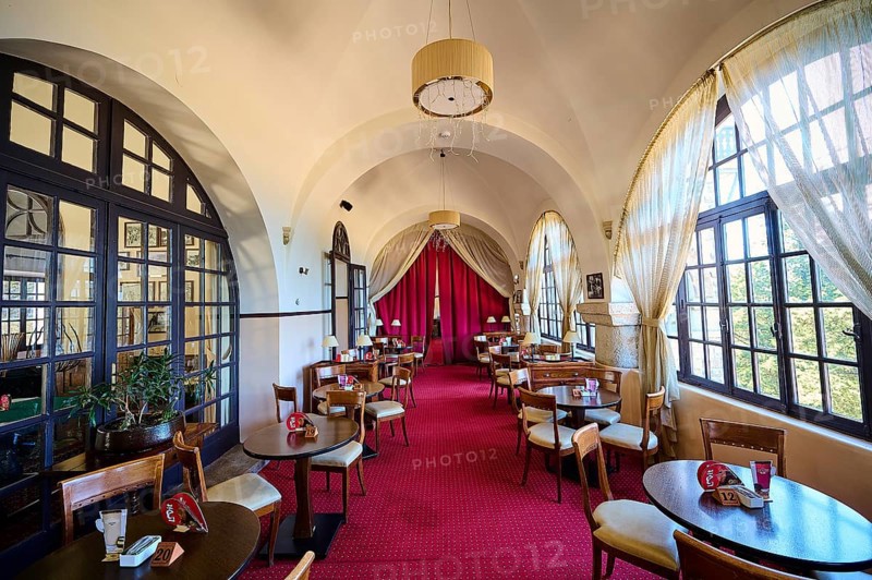 A cosy café with red carpets, tables and chairs under arched windows that let in natural light, Elafos Hotel, Profitis Ilias, Rhodes, Dodecanese, Greek Islands, Greece, Europe