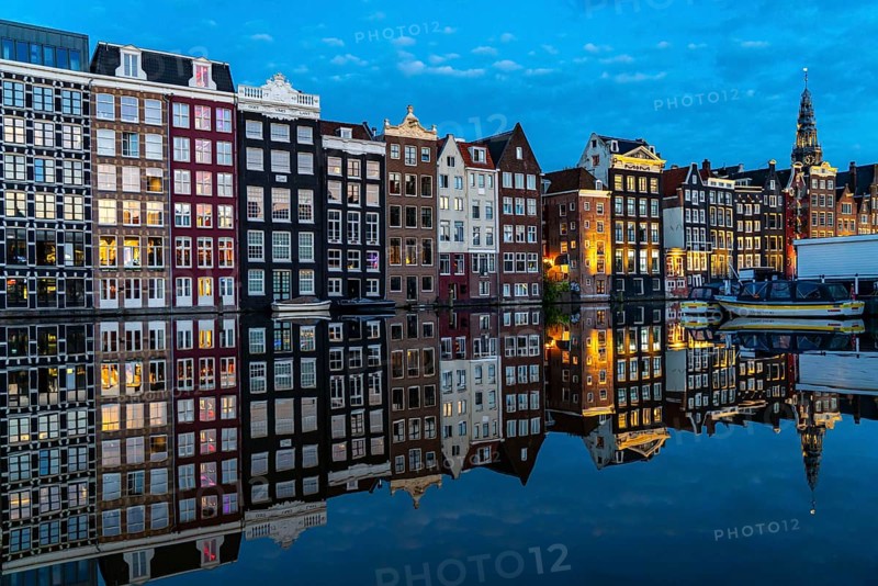 Canal houses on the Damrak, in the centre of the old town of Amsterdam, harbour, starting point of many canal tours, in the evening, church tower of the Oude Kerk, Netherlands