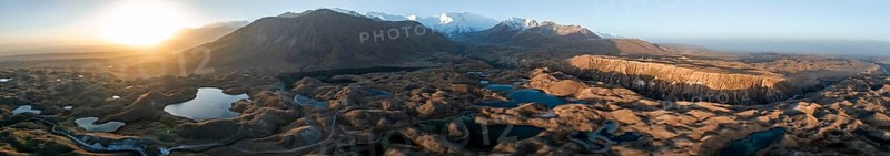 Panorama, White glaciated and snow-covered mountain peak Pik Lenin at sunrise, hilly landscape with golden meadows and lakes, aerial view, Trans Alay Mountains, Pamir Mountains, Osh Province, Kyrgyzstan, Asia