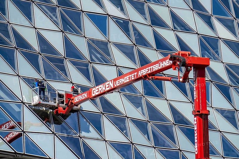 Building cleaners cleaning window panes, cleaning a facade, lorry working platform of the German rental company Gerken, the Antwerp Port Authority building, Havenhuis, former fire brigade barracks in the harbour, renovated and with an attached glass structure, in the shape of a ship's hull, administrative headquarters of the Antwerp Port Authority, designed by Zaha Hadid, Antwerp, Flanders, Belgium, Europe
