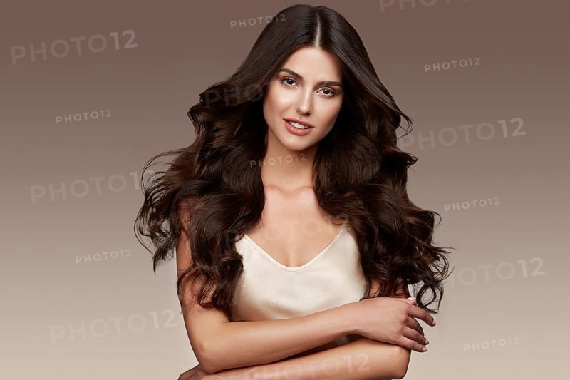 Beautiful brown-haired girl with a perfectly curls hair, and classic make-up. Beauty face and hair. Picture taken in the studio