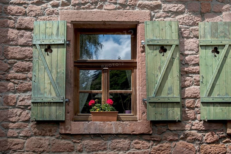 Window with green shutters and a flower pot with geraniums in a red sandstone house, Palatinate Forest, Southern Palatinate, Palatinate, Rhineland-Palatinate, Germany, Europe