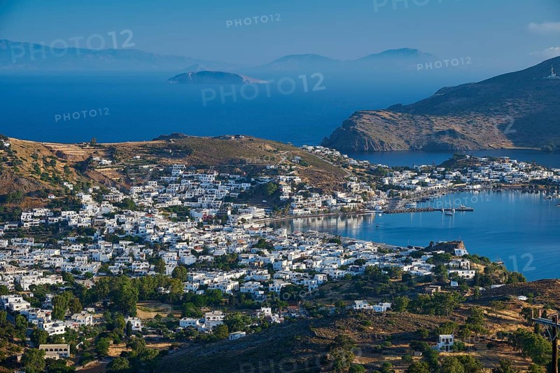 White painted houses of a coastal town, embedded in hilly landscape, surrounded by blue sea, Skala, Patmos, Dodecanese, Greek Islands, Greece, Europe