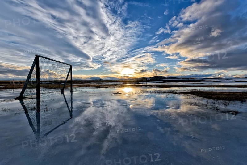 Sunset over clouds, football playground flooded with melting snow, winter, farm Mödrudalur located between lake Myvatn and Egilsstadir, northeast Iceland