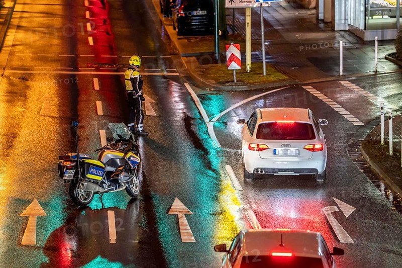 Policeman with motorbike, in rainy weather, blocking a road, police motorbike with blue light