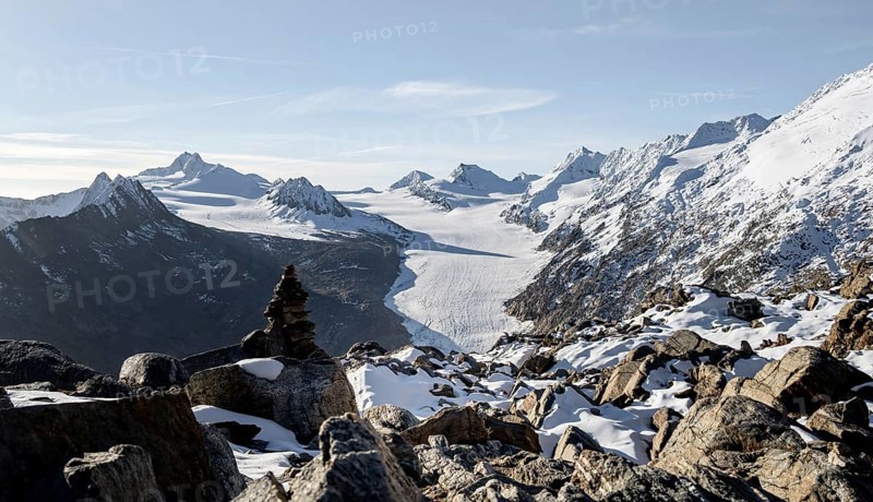 Cairn on the hiking trail to Ramoljoch with snow in autumn, mountain panorama and glacier, view of Gurgler Ferner with summit Hochwilde and Falschungsspitze, in the morning light, Ötztal Alps, Tyrol, Austria, Europe