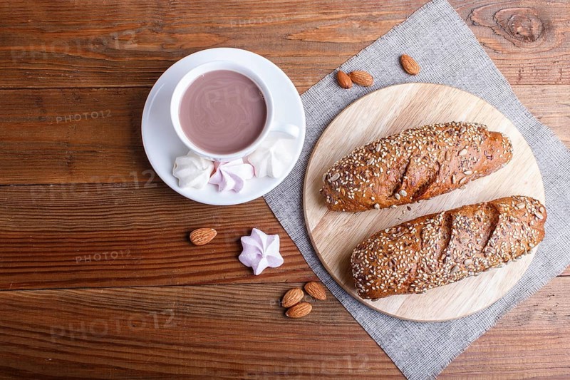 Rye bread with sunflower seeds, sesame and flax with cup of cocoa on brown wooden background. top view, copy space