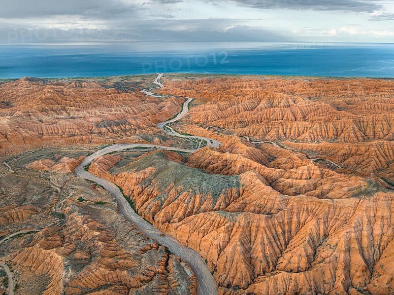 River bed runs through a landscape of eroded hills, badlands, Issyk Kul Lake in the background, aerial view, Canyon of the Forgotten Rivers, Issyk Kul, Kyrgyzstan, Asia