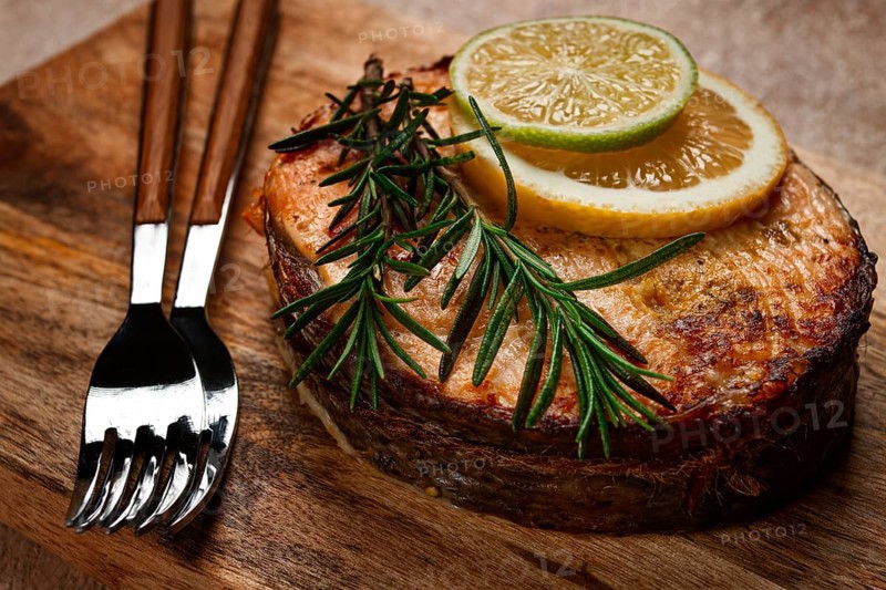 Salmon steak, fried, on a cutting board, top view, rosemary, lemon and lime, homemade, one serving, no people