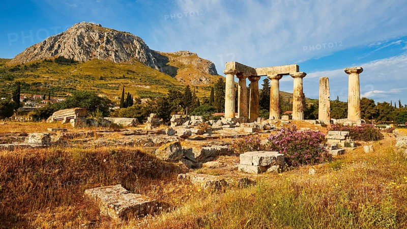 Archaic Temple of Apollo, Doric columns, Wide field of ruins with ancient columns, wild flowers and mountains in the distance, Archaeological site, Archea Korinthos, Corinth, Peloponnese, Greece, Europe