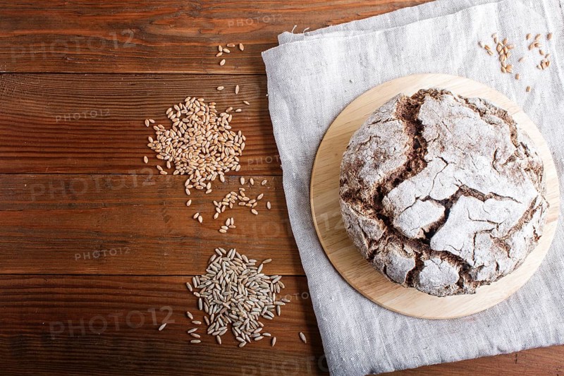 Yeast free homemade bread with whole rye and wheat grains on rustic wooden background. Top view, copy space