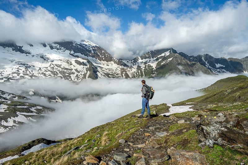 Mountaineer on a hiking trail with high fog in the valley, summit Hochfeiler, Hoher WeiÃŸzint and Hochsteller with clouds, glacier Schlegeiskees, Berliner Höhenweg, Zillertal Alps, Tyrol, Austria, Europe