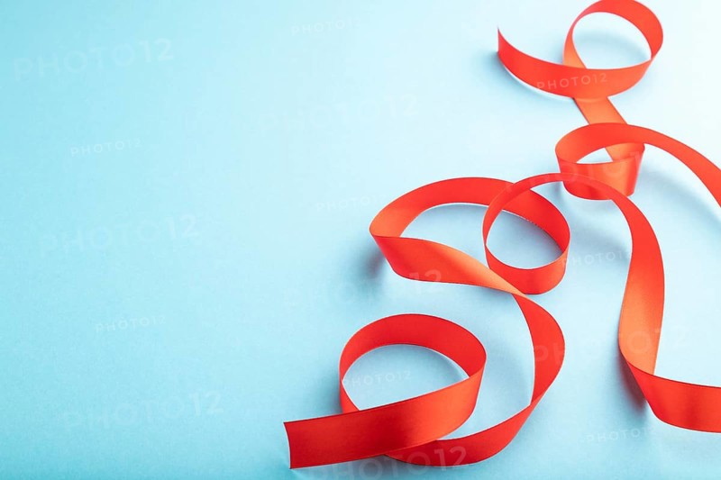 Red coral ribbon on a blue pastel background. Celebration concept. Side view, copy space