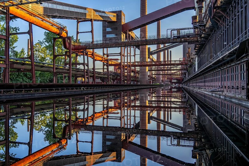 Zollverein coking plant at the Zeche Zollverein, conveyor bridges, chimneys, coke oven batteries are reflected in the rainwater that has collected in the printing press track, North Rhine-Westphalia, Germany, Europe