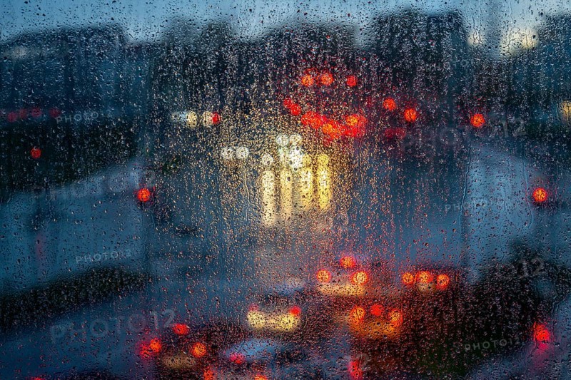 Rainy weather, road traffic, raindrops on a window pane, behind, blurred, lights of vehicles on a rain-soaked road, traffic light, tail lights, headlights, symbolic image