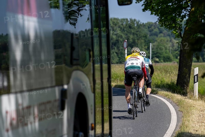 Road cyclist on a country road followed by a local bus that cannot overtake the cyclists on a bend