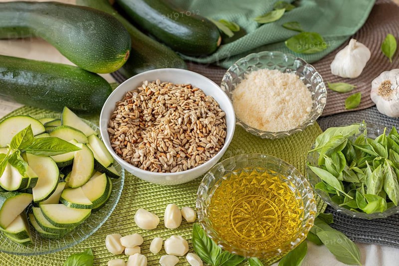 Pesto ingredients such as courgette, basil, sunflower seeds, parmesan, garlic and olive oil on textiles