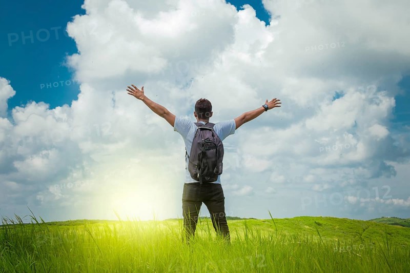 Backpacker man in the field spreading his hands, concept of successful man spreading his hands