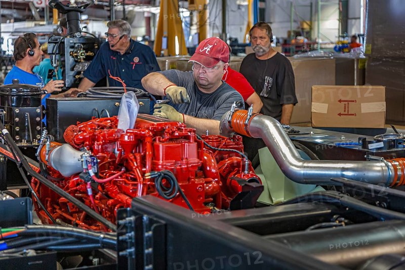 Worker installing a Cumins ISL diesel engine on chassis at Tiffin Motorhomes factory in Red Bay, Alabama, USA, North America