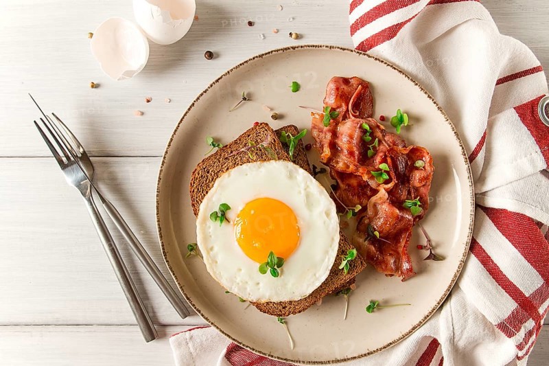 Breakfast, fried egg with bacon, micro-green, on a light background, no people, selective focus