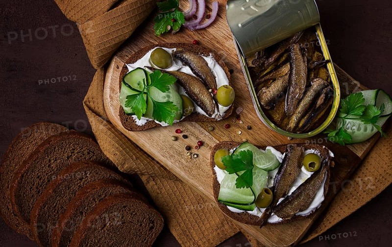 Sandwiches, black bread with sprats, cream cheese, cucumbers, on a cutting board, top view, close-up, no people