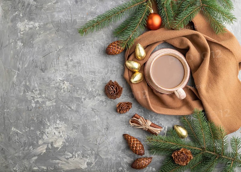 Christmas or New Year composition. Decorations, cones, cinnamon, fir and spruce branches, cup of coffee, wool scarf on a gray concrete background. Top view, copy space, flat lay