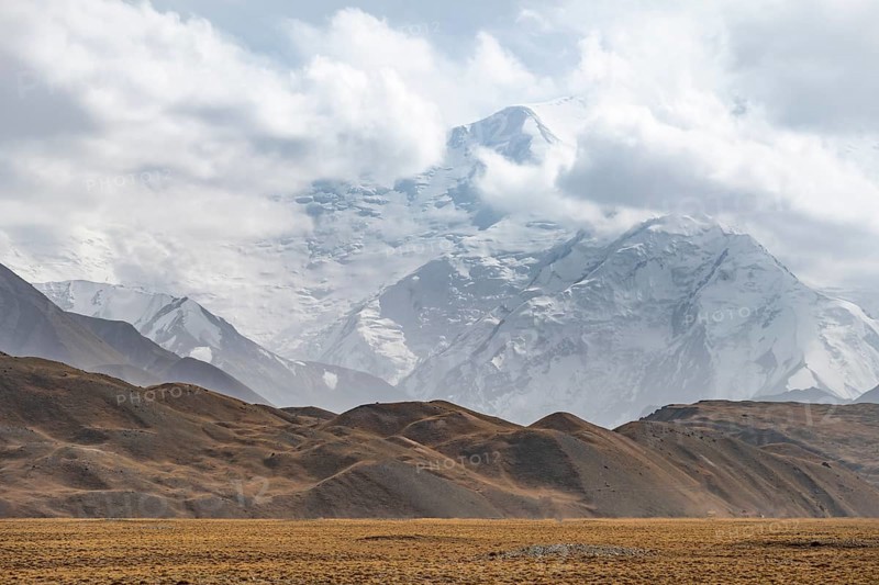 Glaciated, cloud-covered mountain peaks and golden meadows, Lenin Peak, Trans Alay Mountains, Pamir Mountains, Osh Province, Kyrgyzstan, Asia