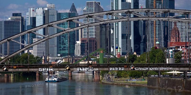 The river Main with the Deutschherrnbrücke bridge and a barge in front of the skyline of Frankfurt am Main, Hesse, Germany, Europe