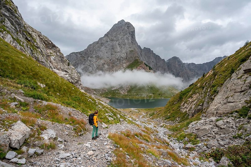 Mountaineer on a hiking trail with a view of rocky, cloud-covered mountains and Wolayersee, hiking trail to Wolayerseehütte, cloud-covered mountain peaks, Carnic Alps, Carnic High Trail, Carinthia, Austria, Europe