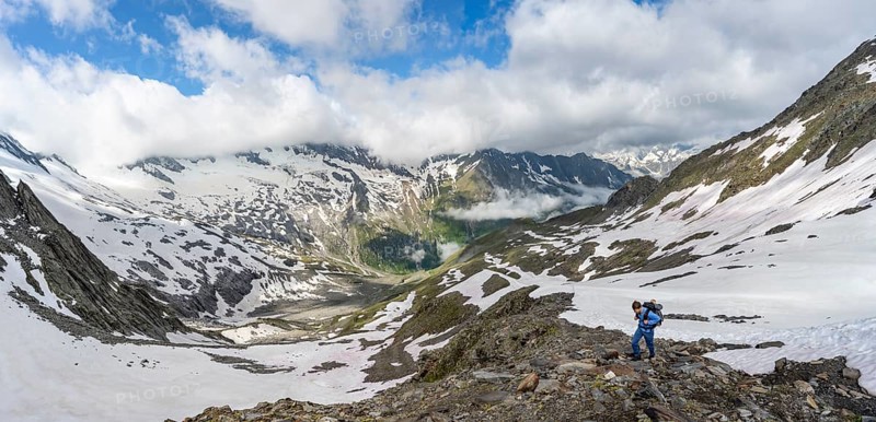 Mountaineer on hiking trail with snow, mountain landscape with summit Hoher WeiÃŸzint and Hochsteller with glacier Schlegeiskees, Berliner Höhenweg, Zillertal Alps, Tyrol, Austria, Europe