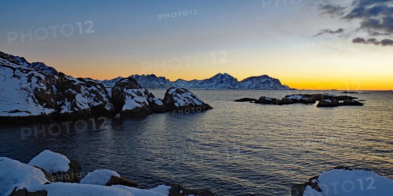 Impressive winter landscape with snow-covered mountains and rocks in a calm sea at sunset, Winter, Nyksund, Langoya, Vesteralen, Nordland, Norway, Europe